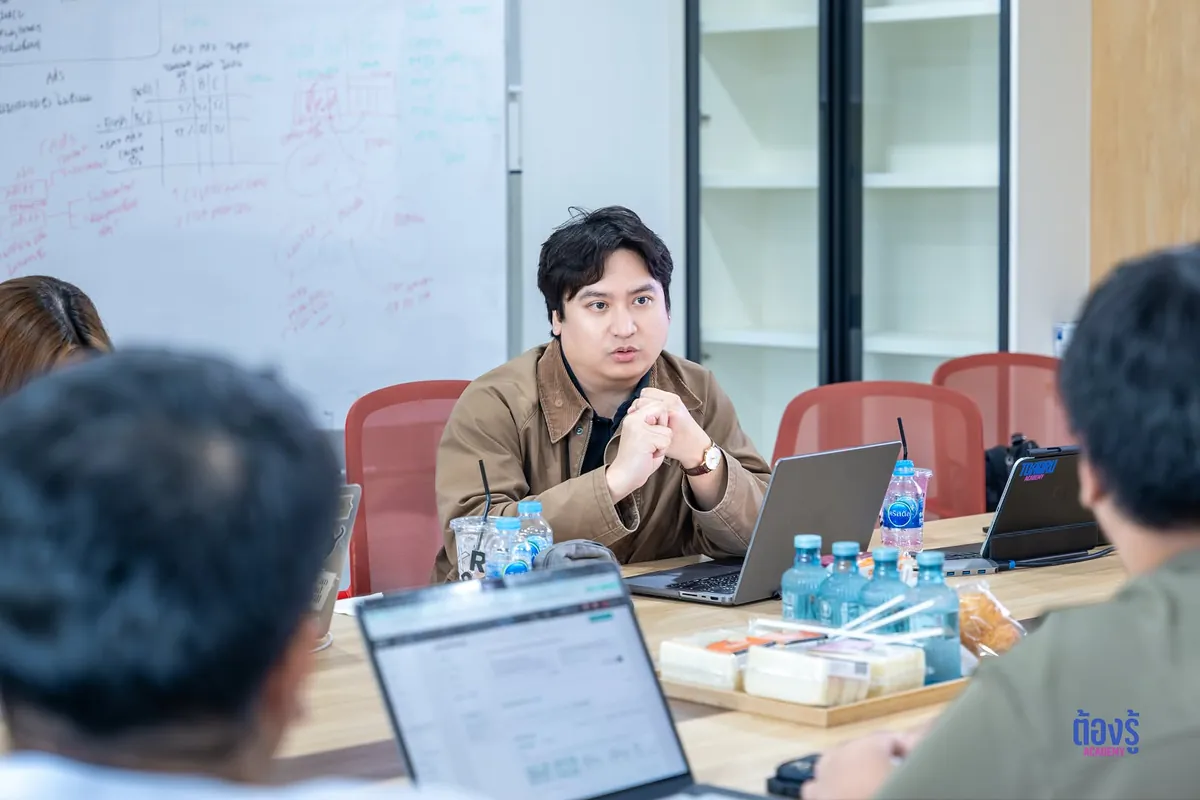 ผู้สอนนั่งที่โต๊ะประชุมรับฟังผู้เรียนที่เปิดโน้ตบุ๊กอยู่ตรงหน้า